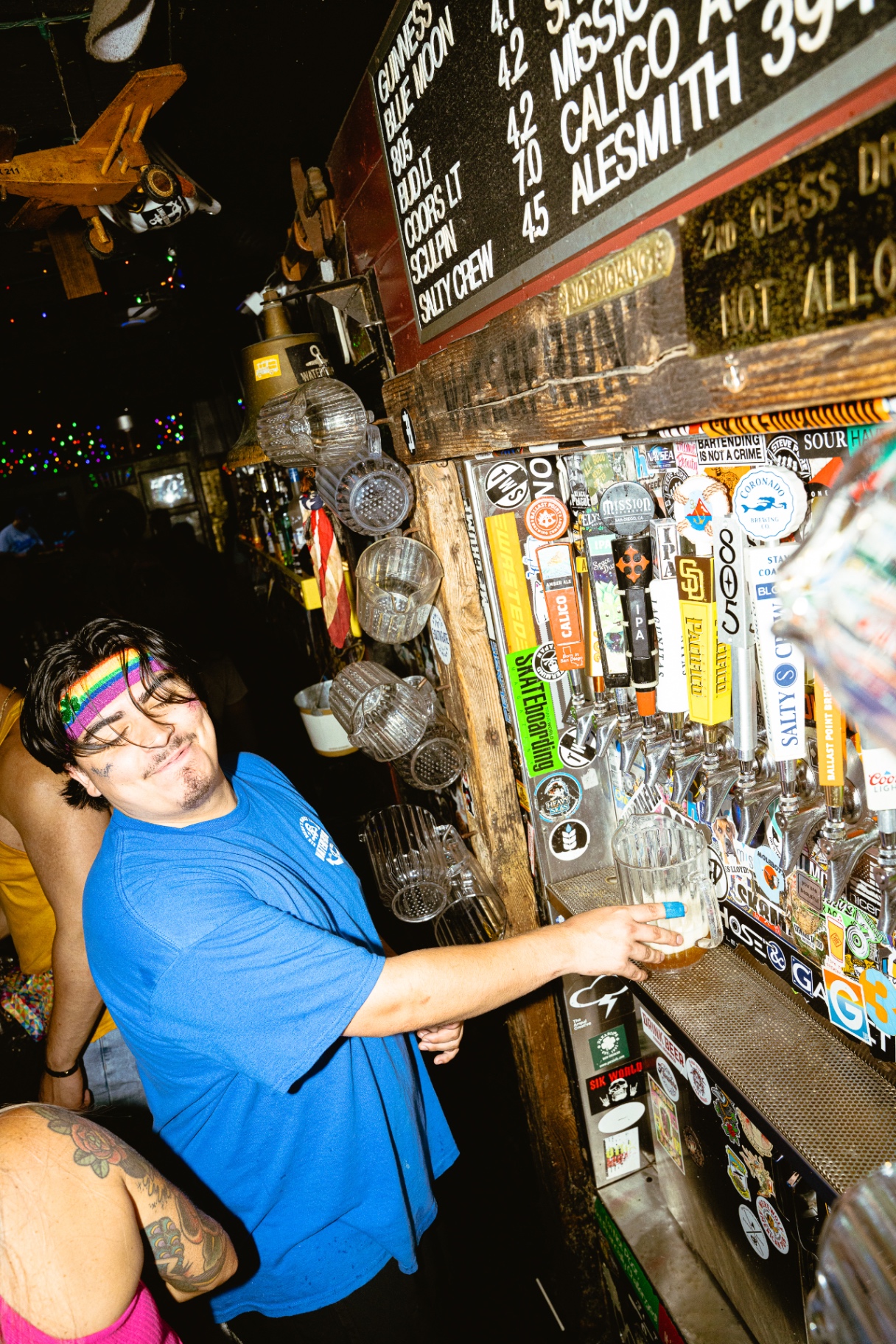 Bartender pouring a beer at the sticker-covered tap wall at Waterfront Bar & Grill